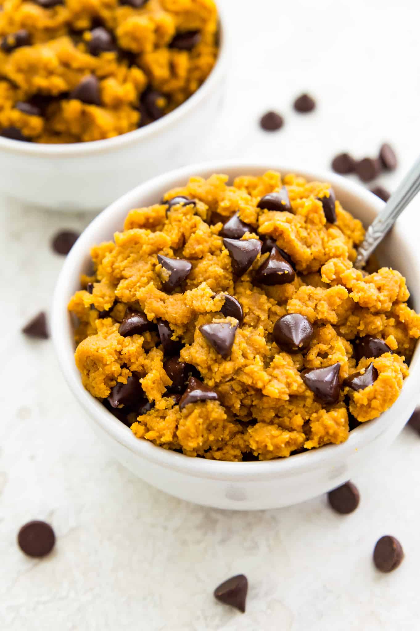 Edible Pumpkin Cookie Dough Recipe A bowl of edible pumpkin cookie dough with chocolate chips and a spoon in it.
