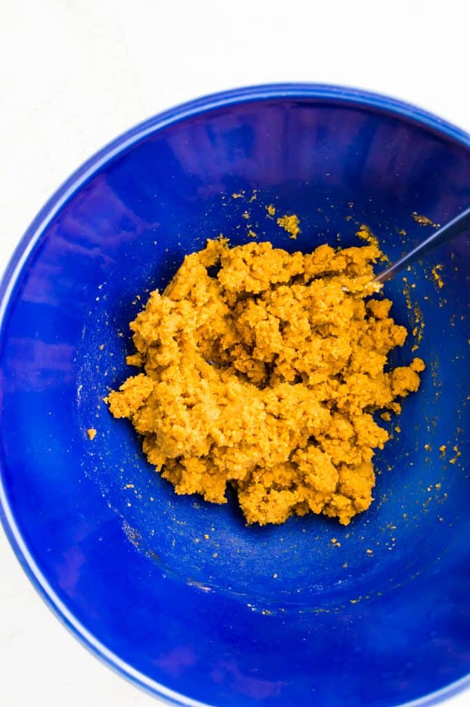 A blue bowl filled with edible pumpkin cookie dough.