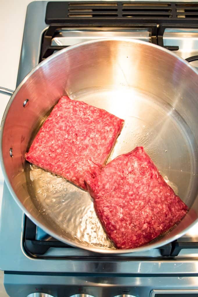 Ground beef cooking in a pot on the stove.