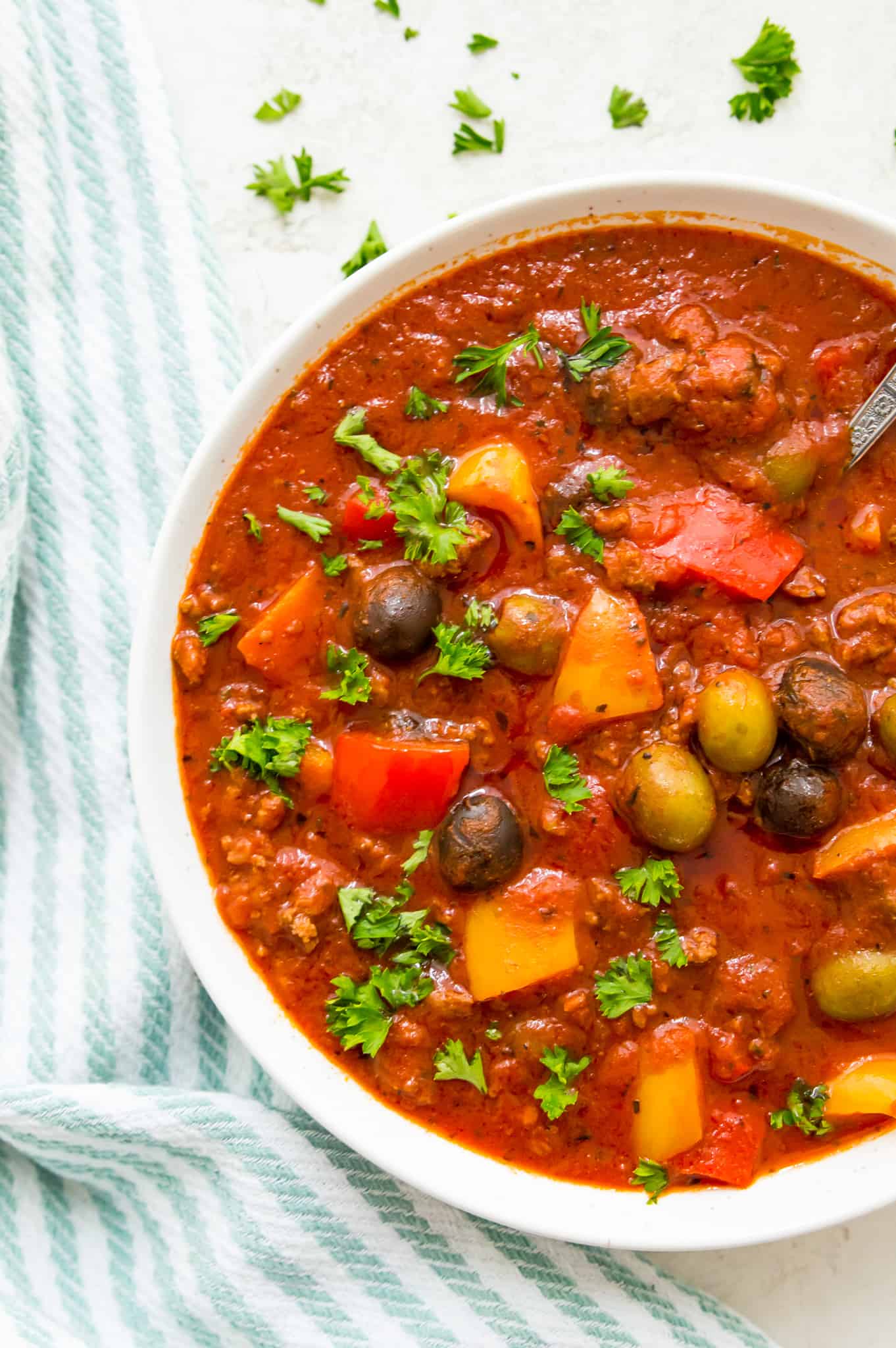 A bowl of healthy meat sauce garnished with fresh parsley.