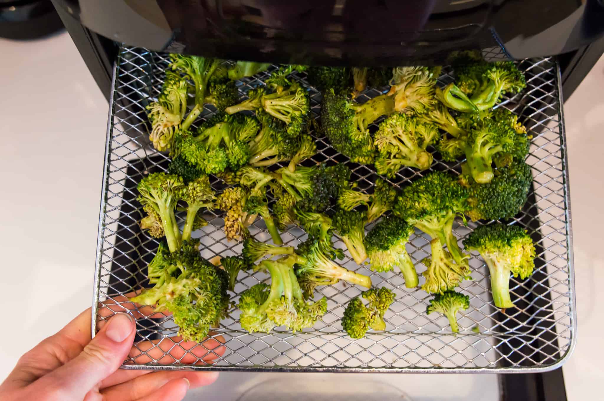 Broccoli pieces on an air fryer tray.