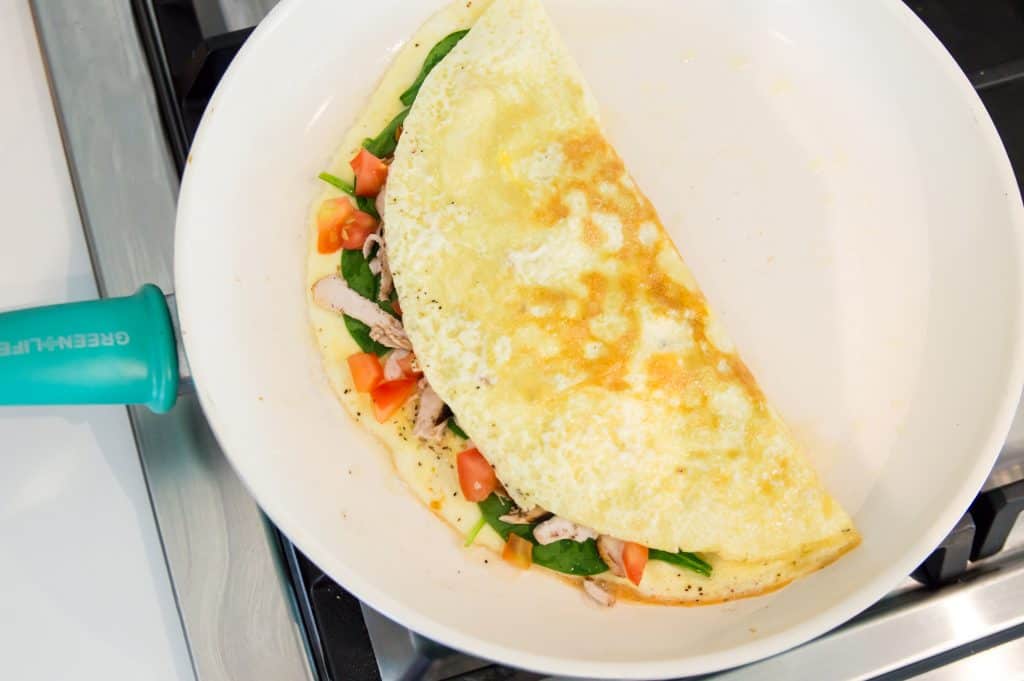 An omelette with chicken being cooked in a pan.