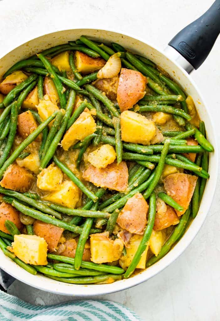 A pan filled with cooked green beans and potatoes. 