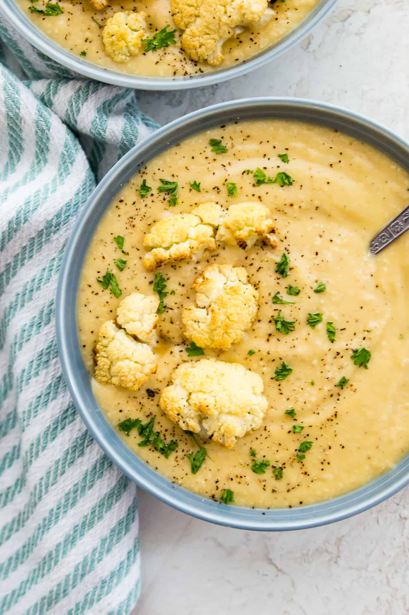 A bowl of Whole30 cauliflower soup garnished with parsley and roasted cauliflower.