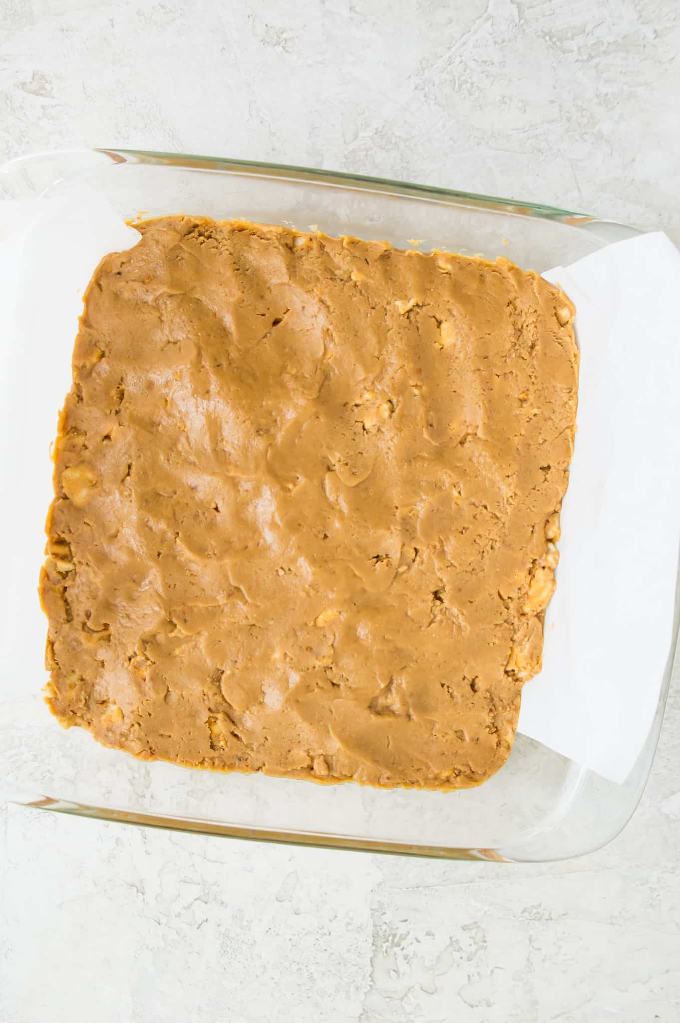A baking pan with peanut butter pressed into it.