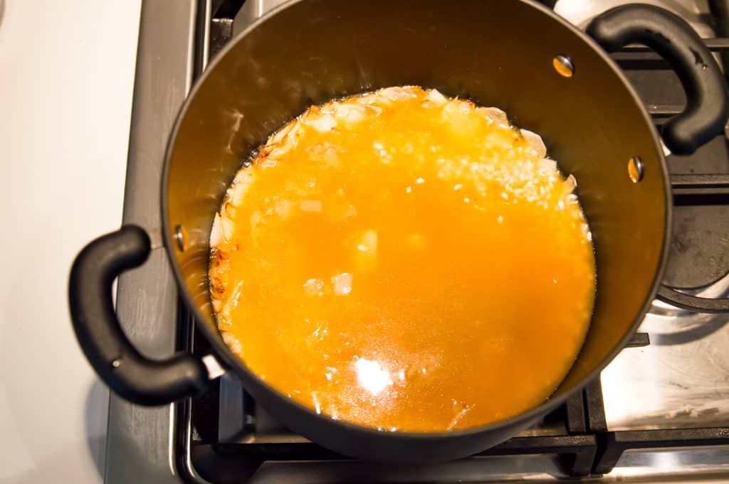 A pot full of pumpkin risotto ingredients on the stove.