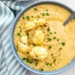 A bowl of creamy cauliflower soup topped with roasted cauliflower and fresh parsley.
