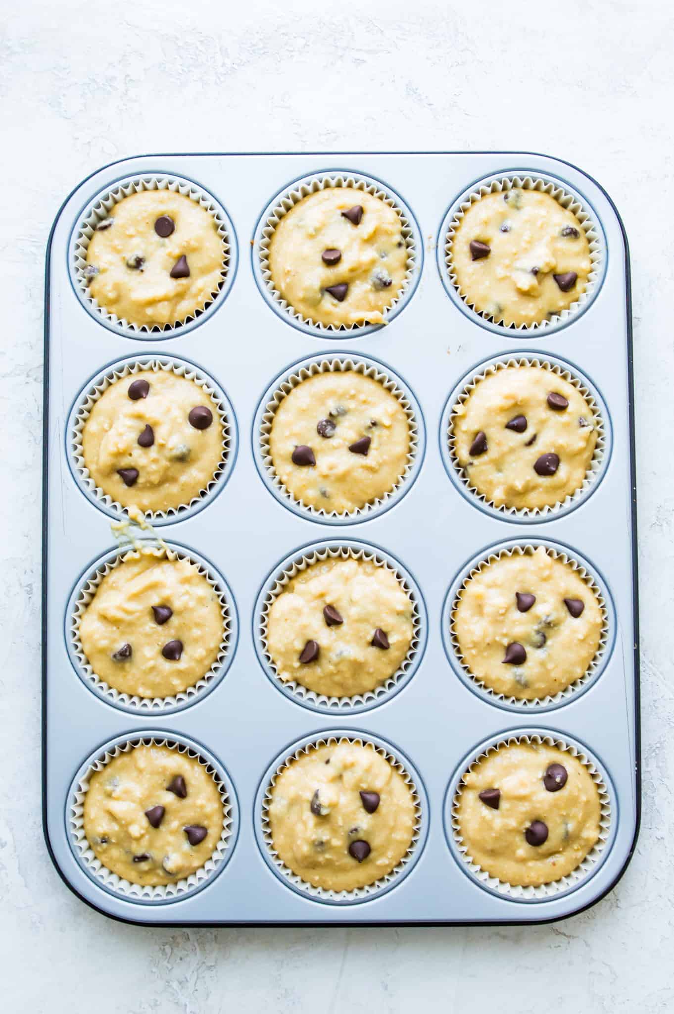 Banana protein muffin batter in muffin cups in a muffin tray.