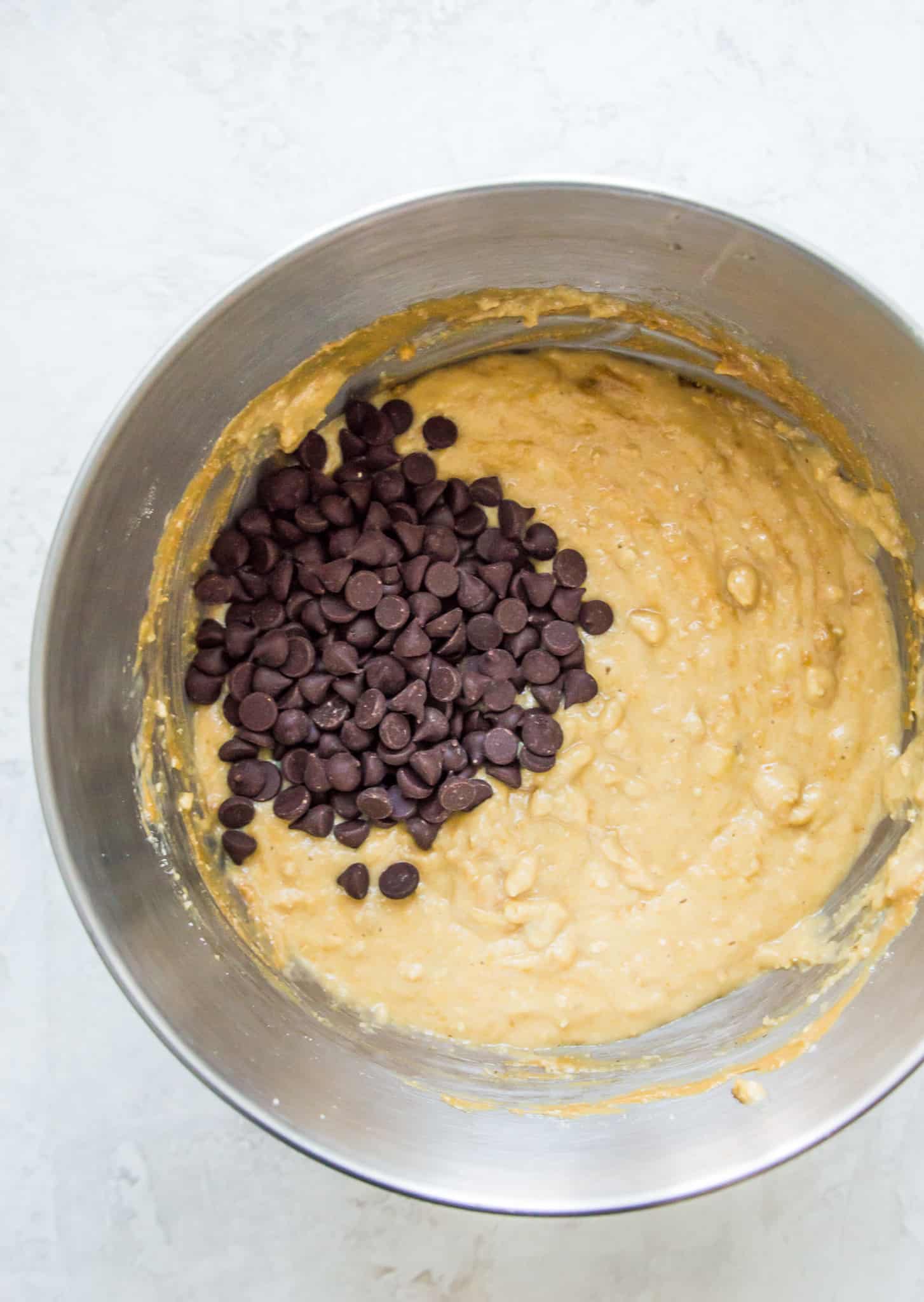 A mixing bowl with muffin batter in it topped with chocolate chips.