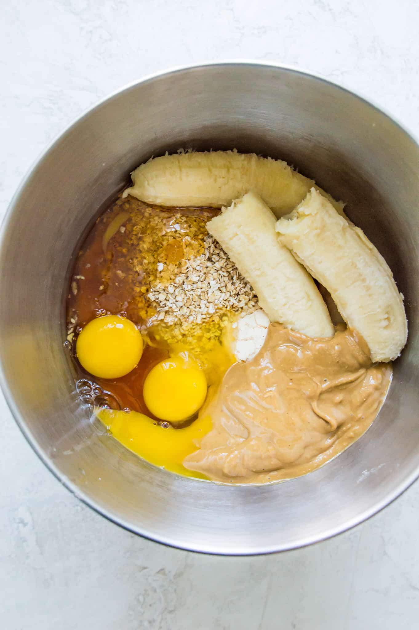 Eggs, peanut butter, bananas and oats in a large bowl.