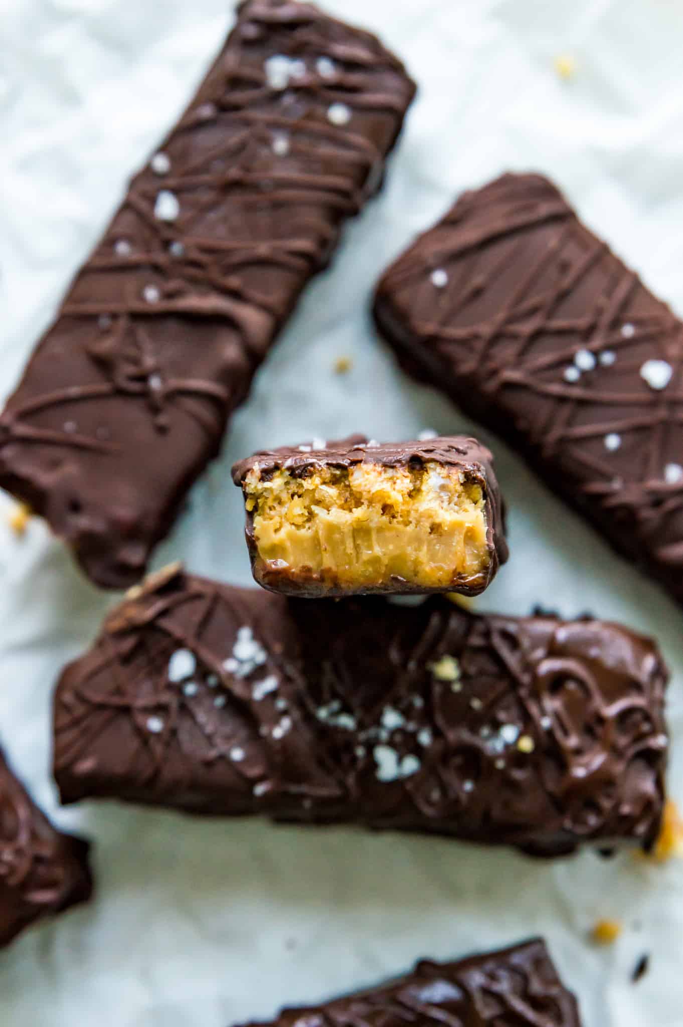 A homemade cereal bar with chocolate drizzled on it and a bite taken out of it.