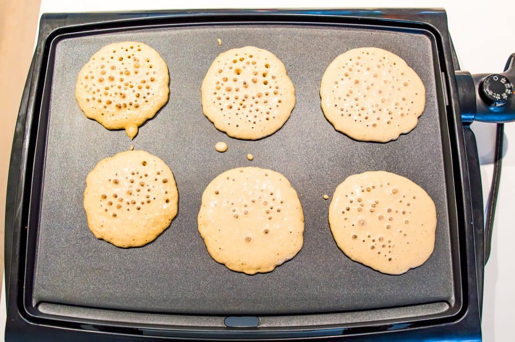 Pancakes being cooked on a griddle.