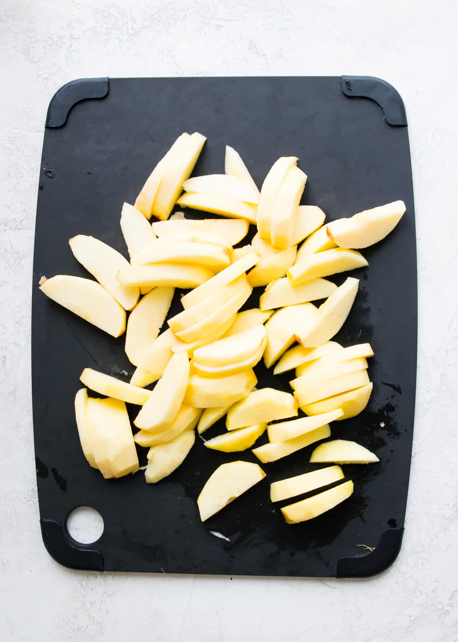 Peeled and sliced apples on a cutting board.