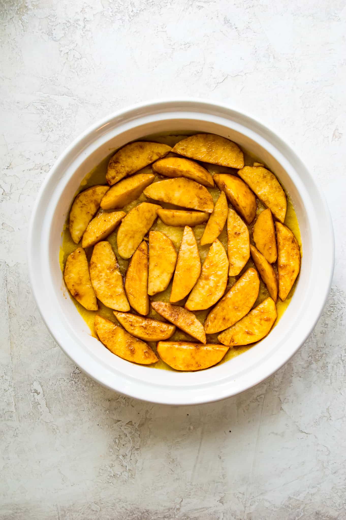 Apple slices coated in sugar in a casserole dish.