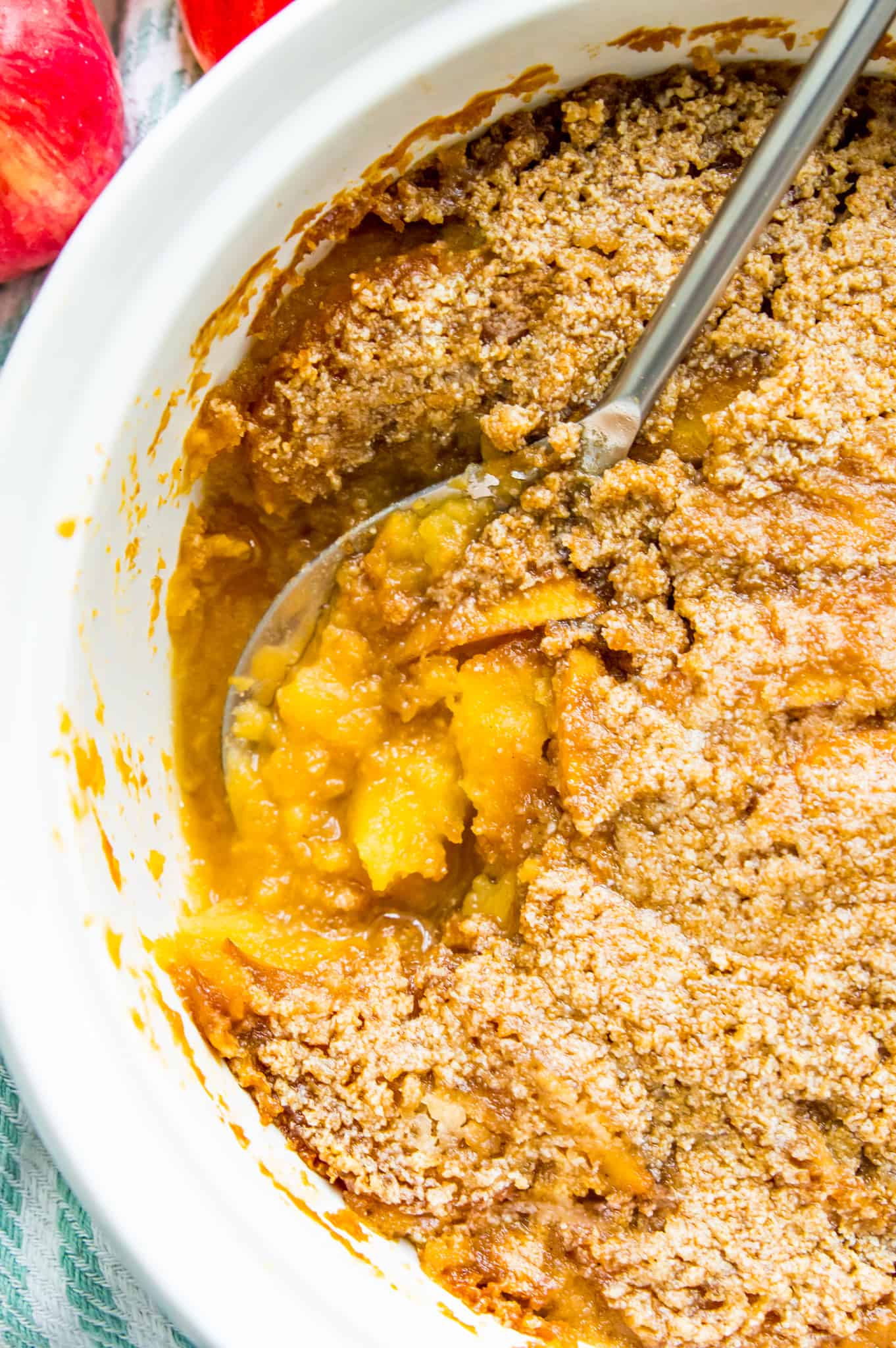 A white casserole dish filled with turnip and apple casserole with a serving spoon in it.