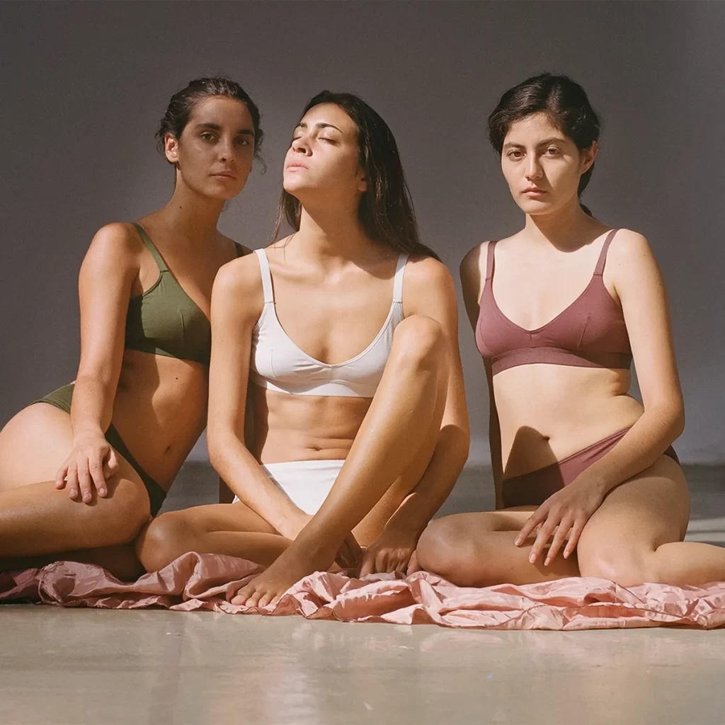 Three women wearing Nude Label bra and underwear sets in green, white and brown
