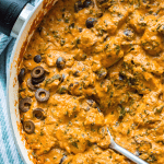 A pan of sun-dried tomato chicken and spinach with a spoon in it