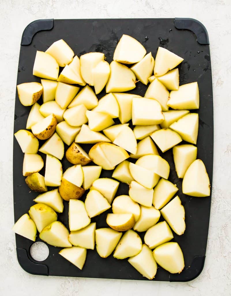 A cutting board with diced potatoes on it.