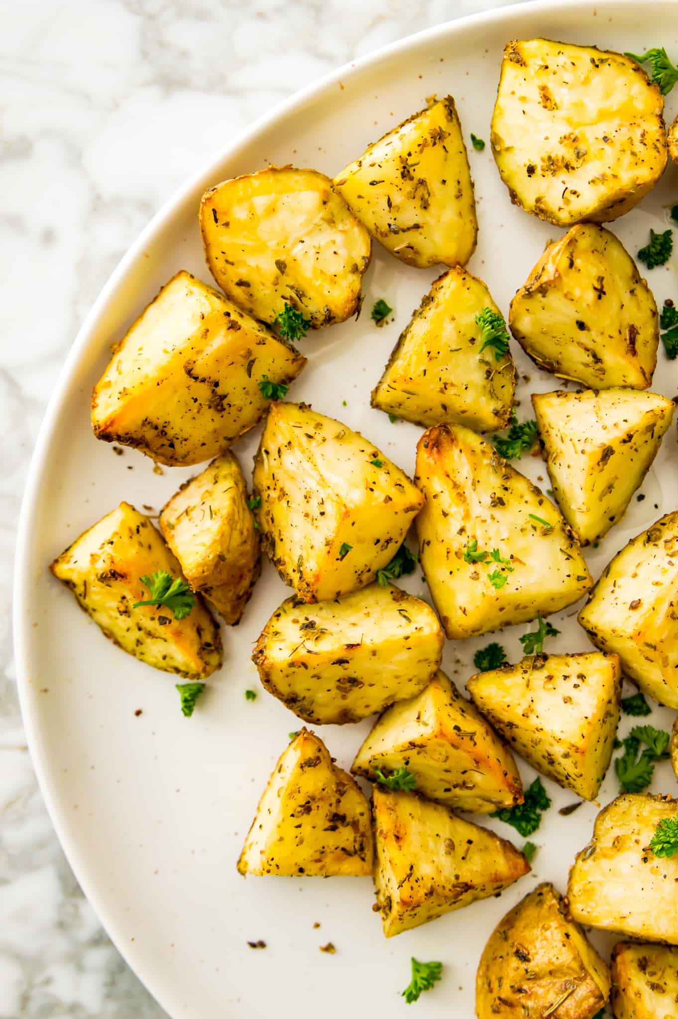 A plate of cooked, diced potatoes garnished with fresh parsley.