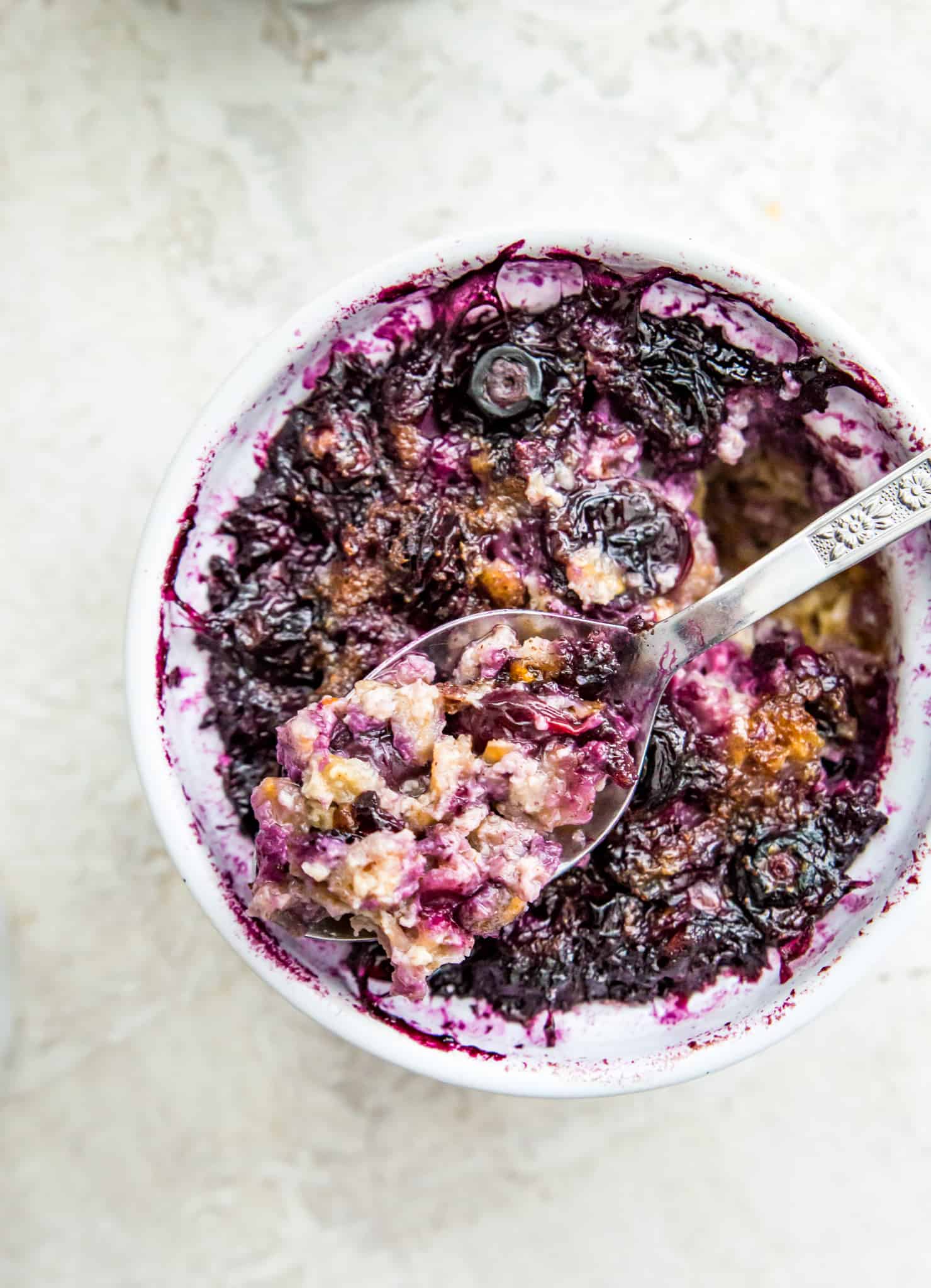 A ramekin filled with baked oatmeal and topped with cooked blueberries.