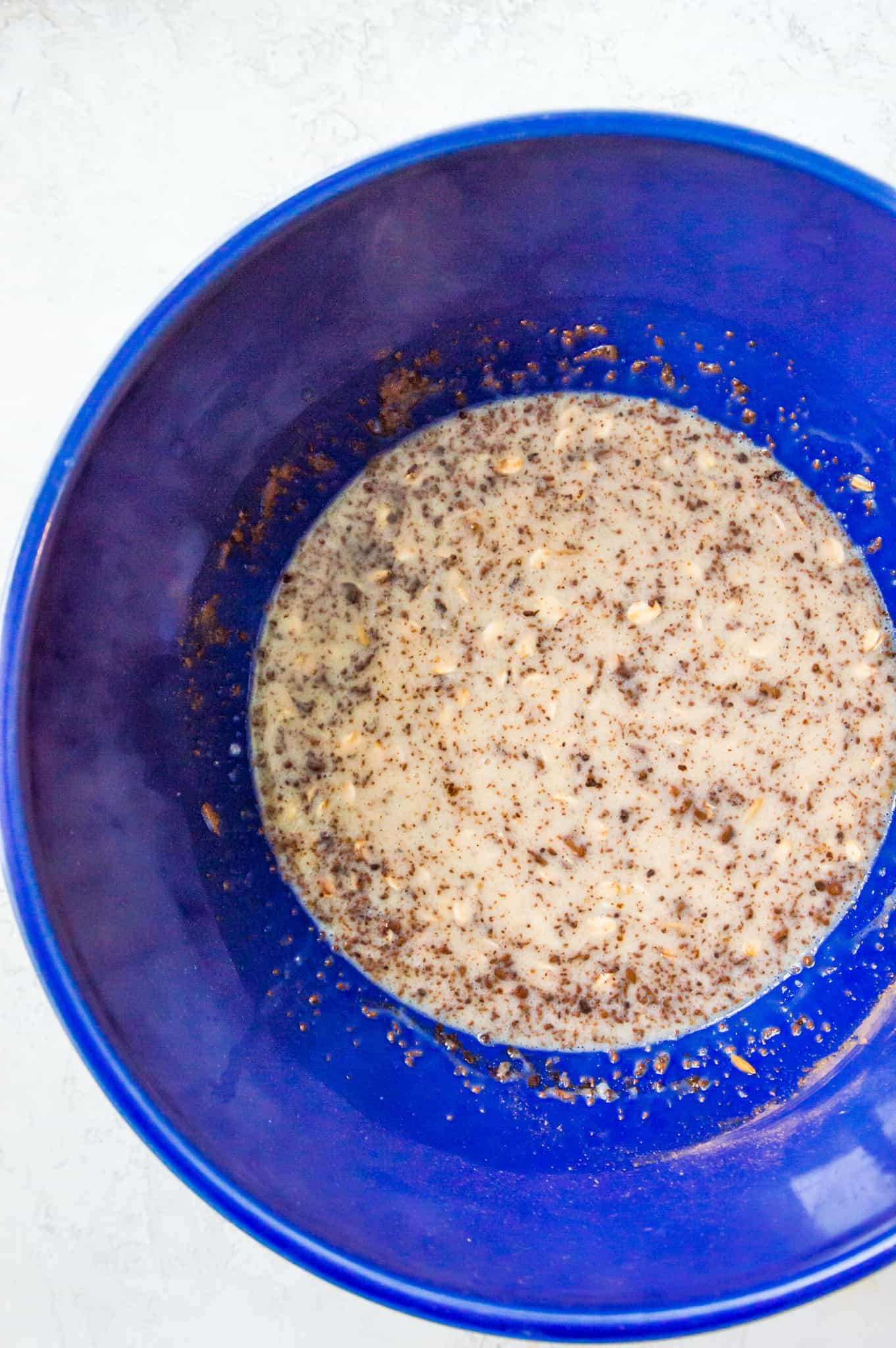 A large blue bowl filled with oats, milk and egg.