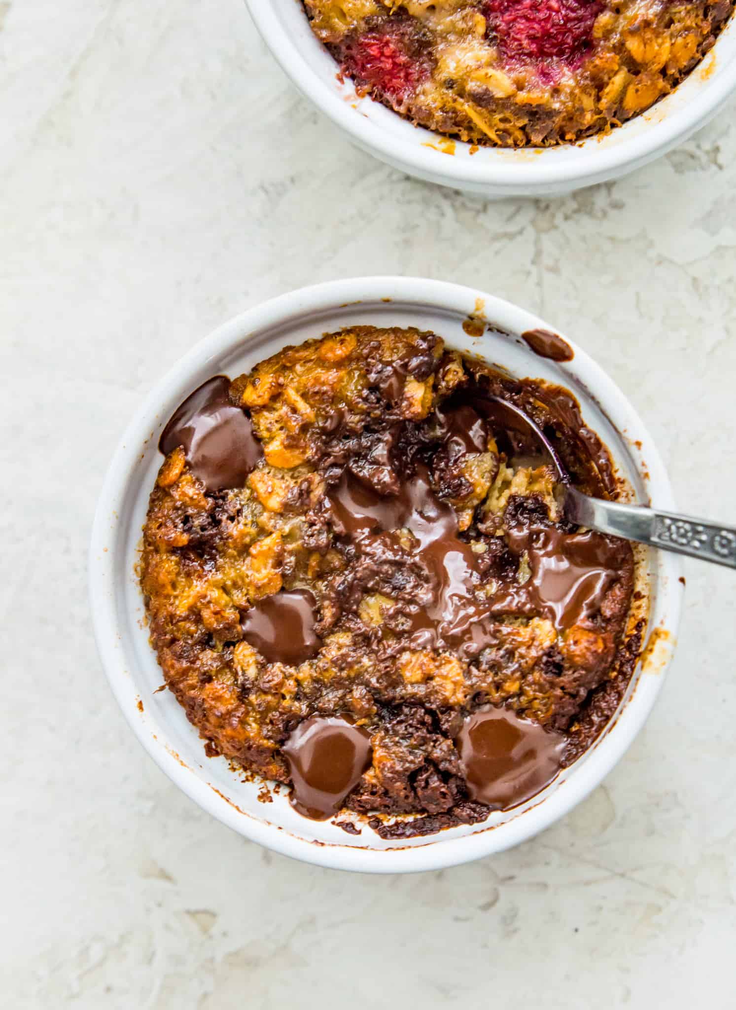 A ramekin filled with chocolate baked oats with a spoon in it.