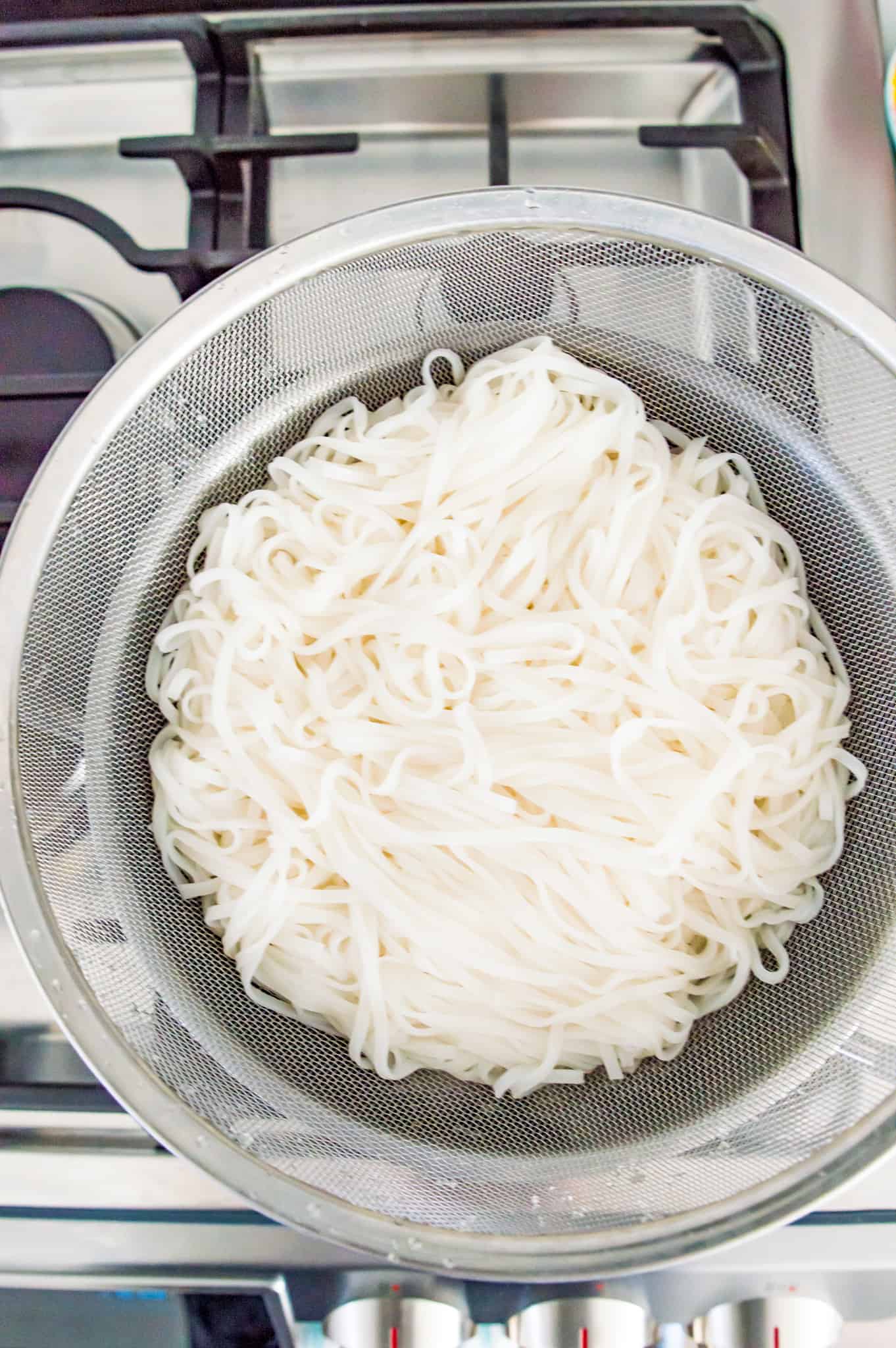 A colander filled with cooked rice noodles