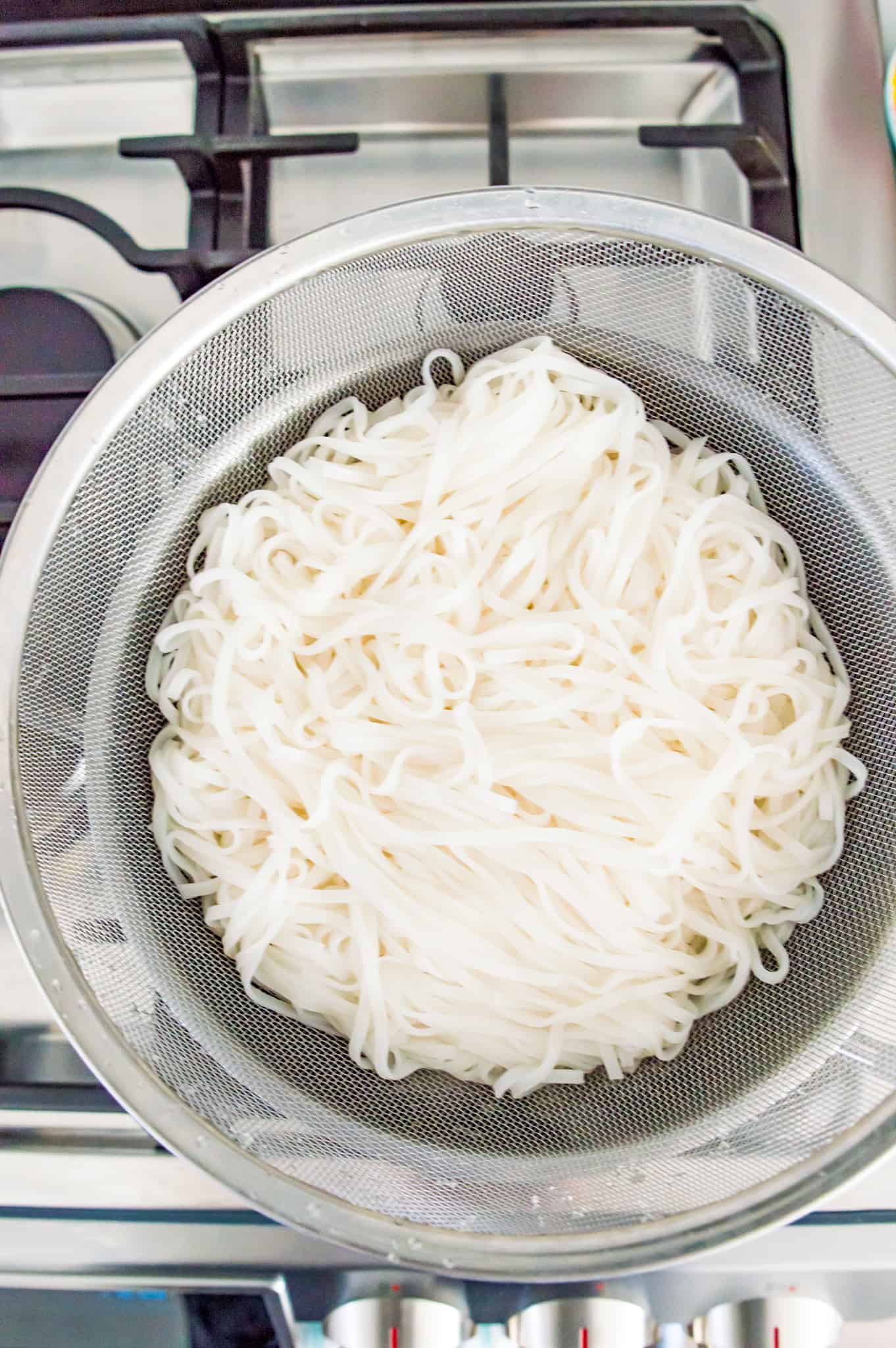 A colander with rice noodles in it.