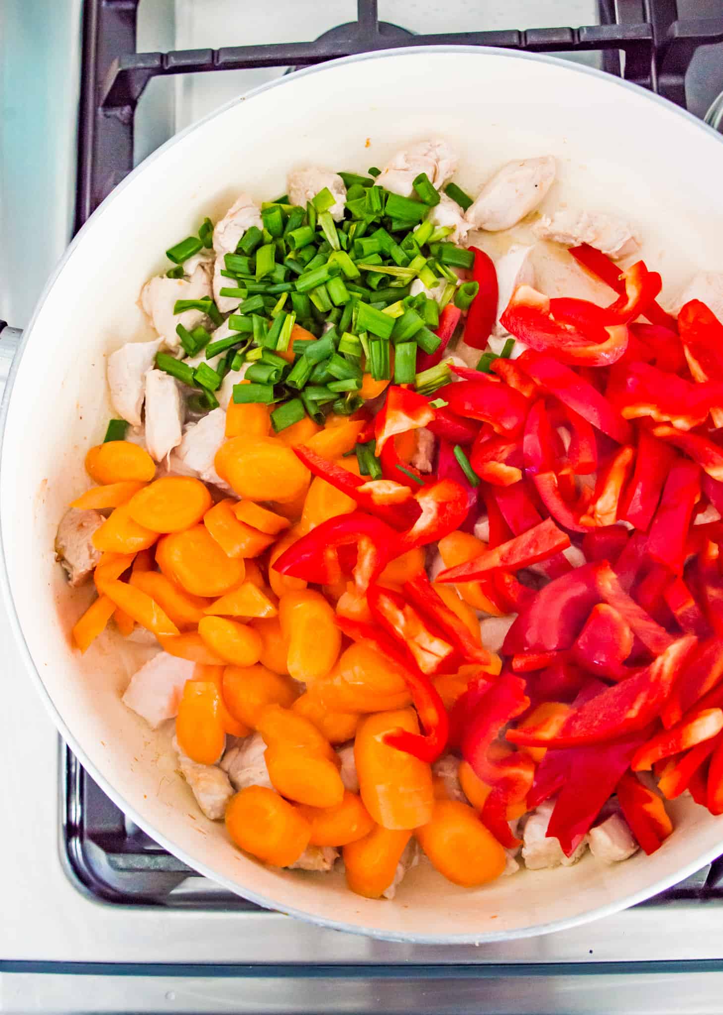 A pan with chopped carrots, green onion and red bell pepper in it.