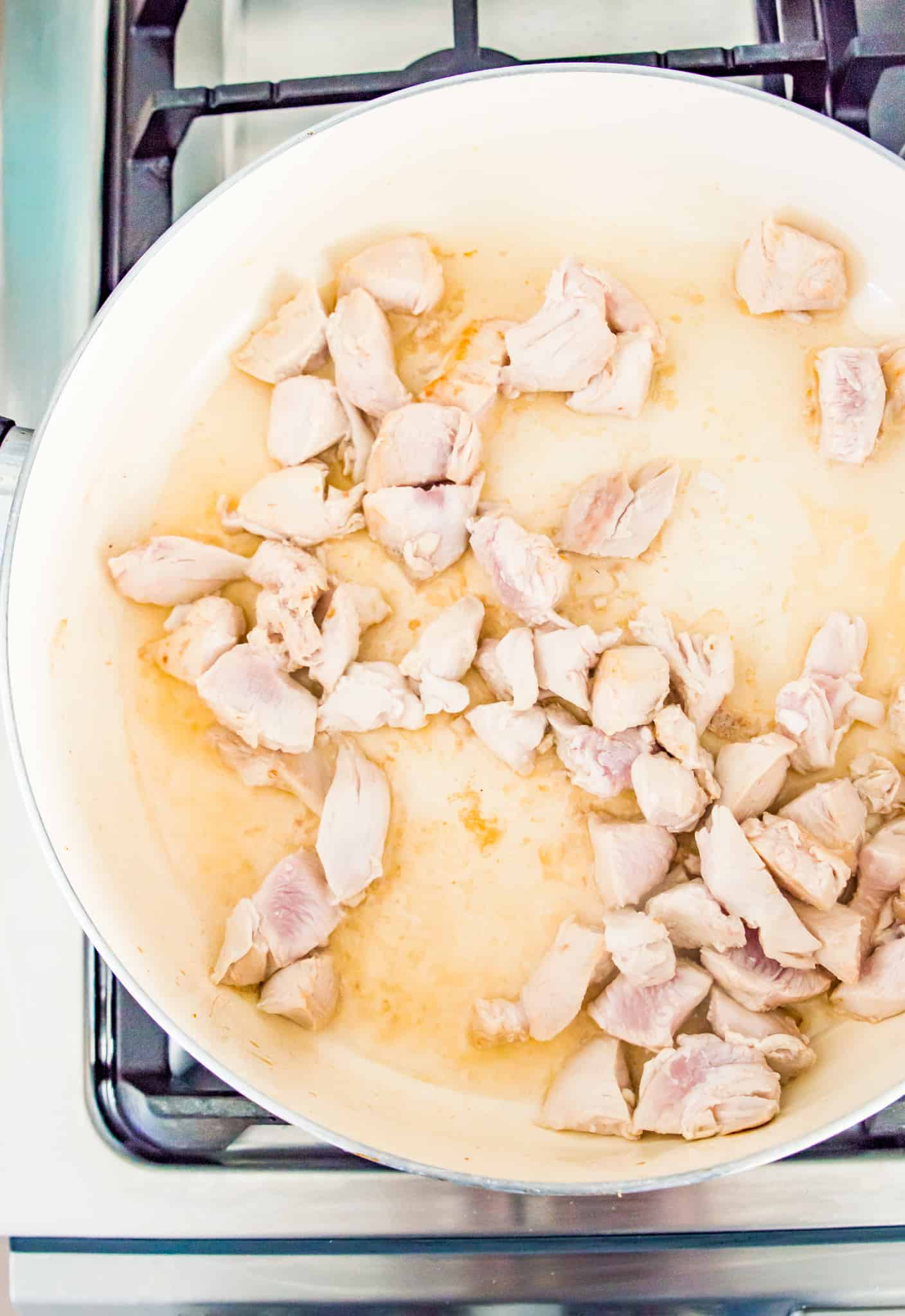 A pan with chicken pieces cooking in it.