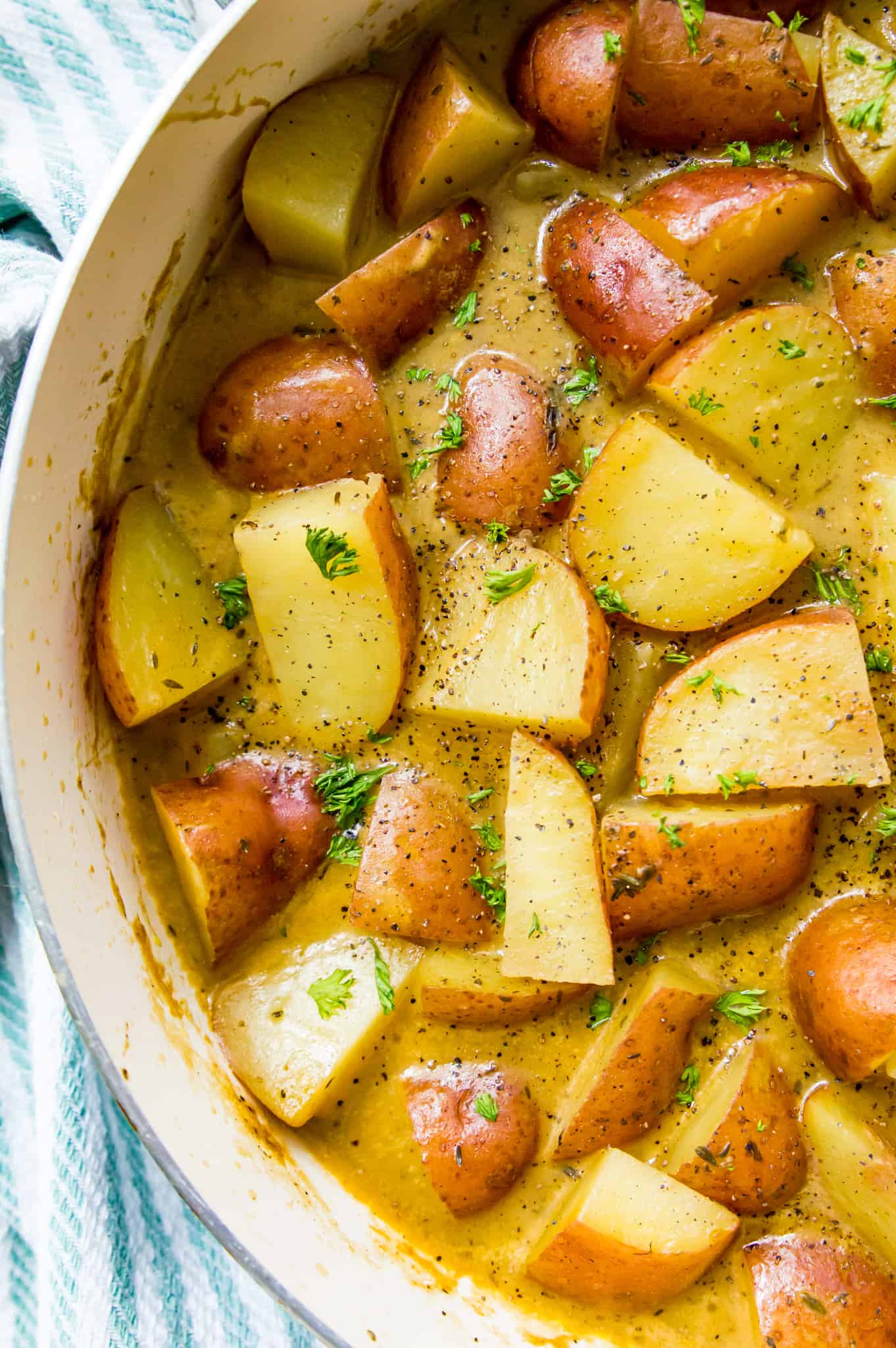 A pan of stewed red potatoes topped with fresh parsley. 