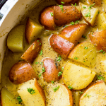 A pan full of stewed potatoes topped with fresh herbs