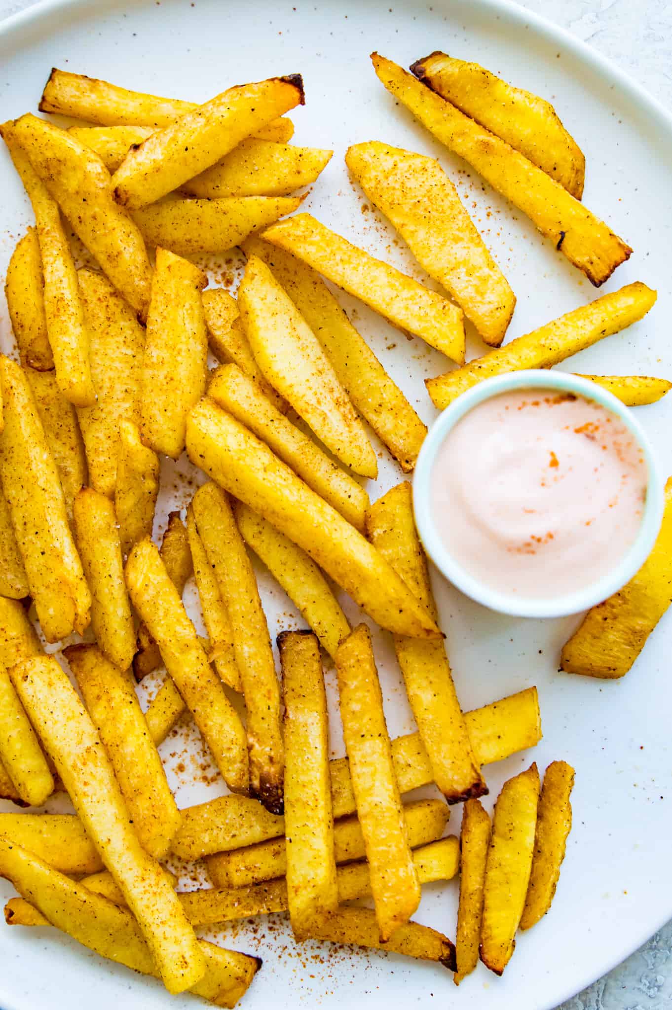 A plate of turnip fries served with a small dish of aioli.