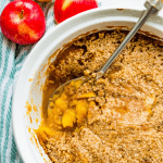 A casserole dish filled with a turnip and apple casserole with a spoon in it