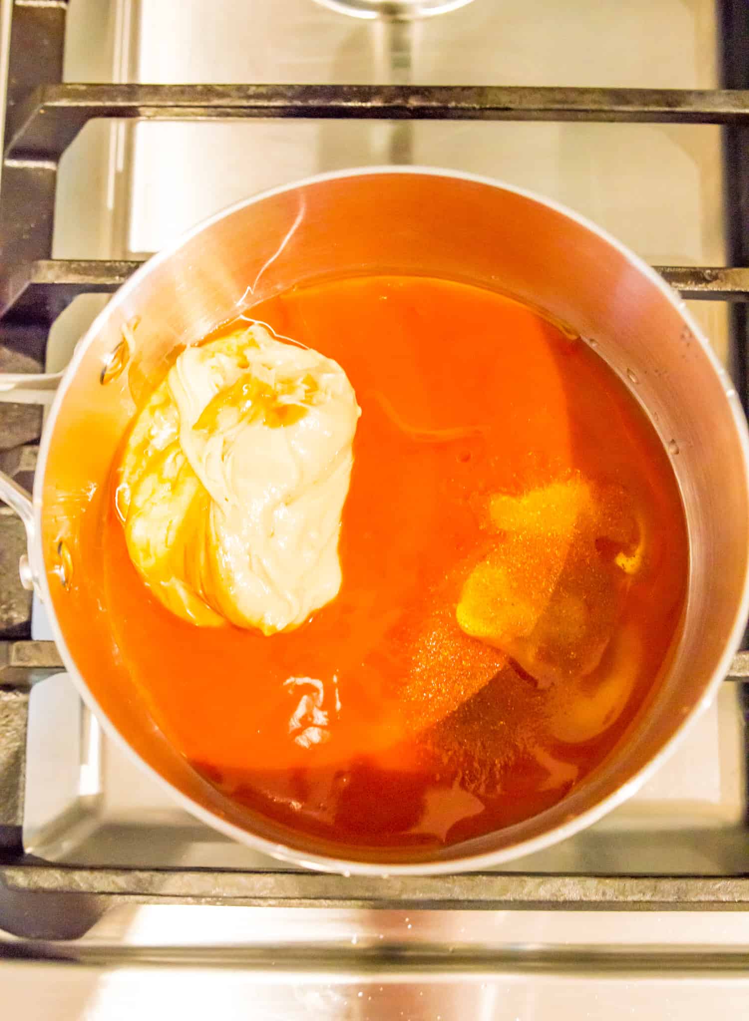 A pot on the stove with ingredients for making vegan buffalo sauce. 