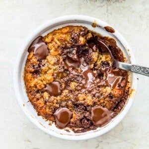 A ramekin filled with baked oats with chocolate chips and a spoon in it.