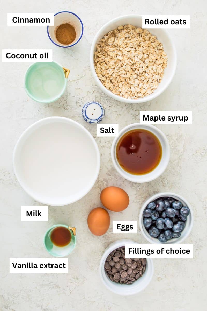 The ingredients needed to make baked oats separated into bowls including rolled oats, ground cinnamon, eggs, maple syrup, coconut oil and vanilla extract.