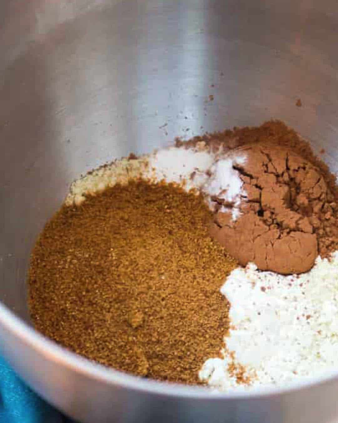 A metal bowl filled with sugar, flour and cocoa powder.