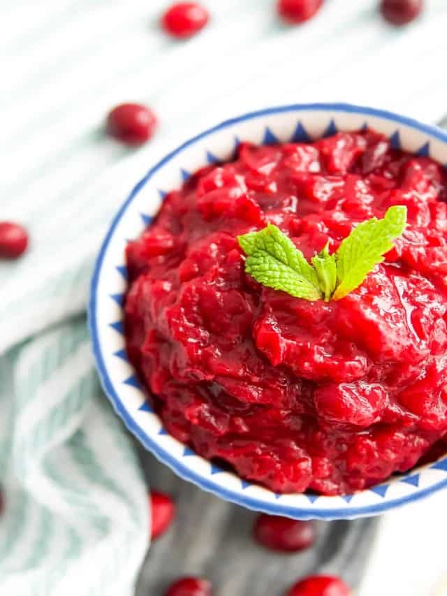 A bowl of cranberry sauce with fresh mint leaves on it for garnish.