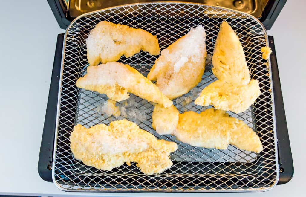 Frozen chicken tenders in an air fryer.