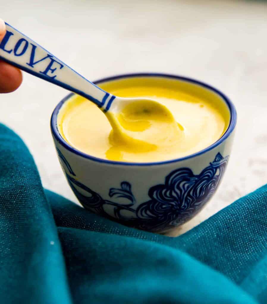 A bowl of honey mustard sauce with a spoon stirring it.