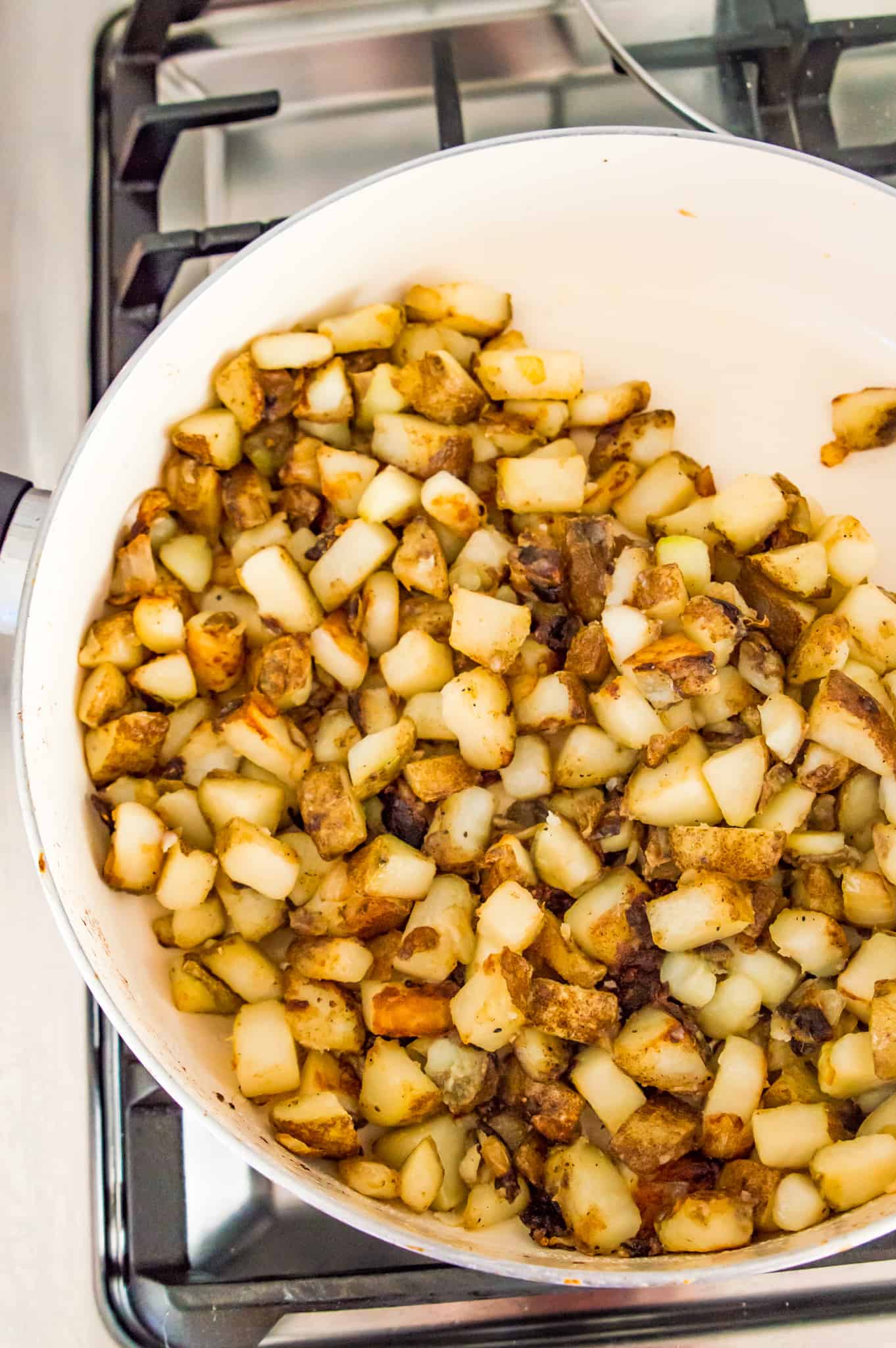 Fried potatoes and onions in a skillet on the stovetop.