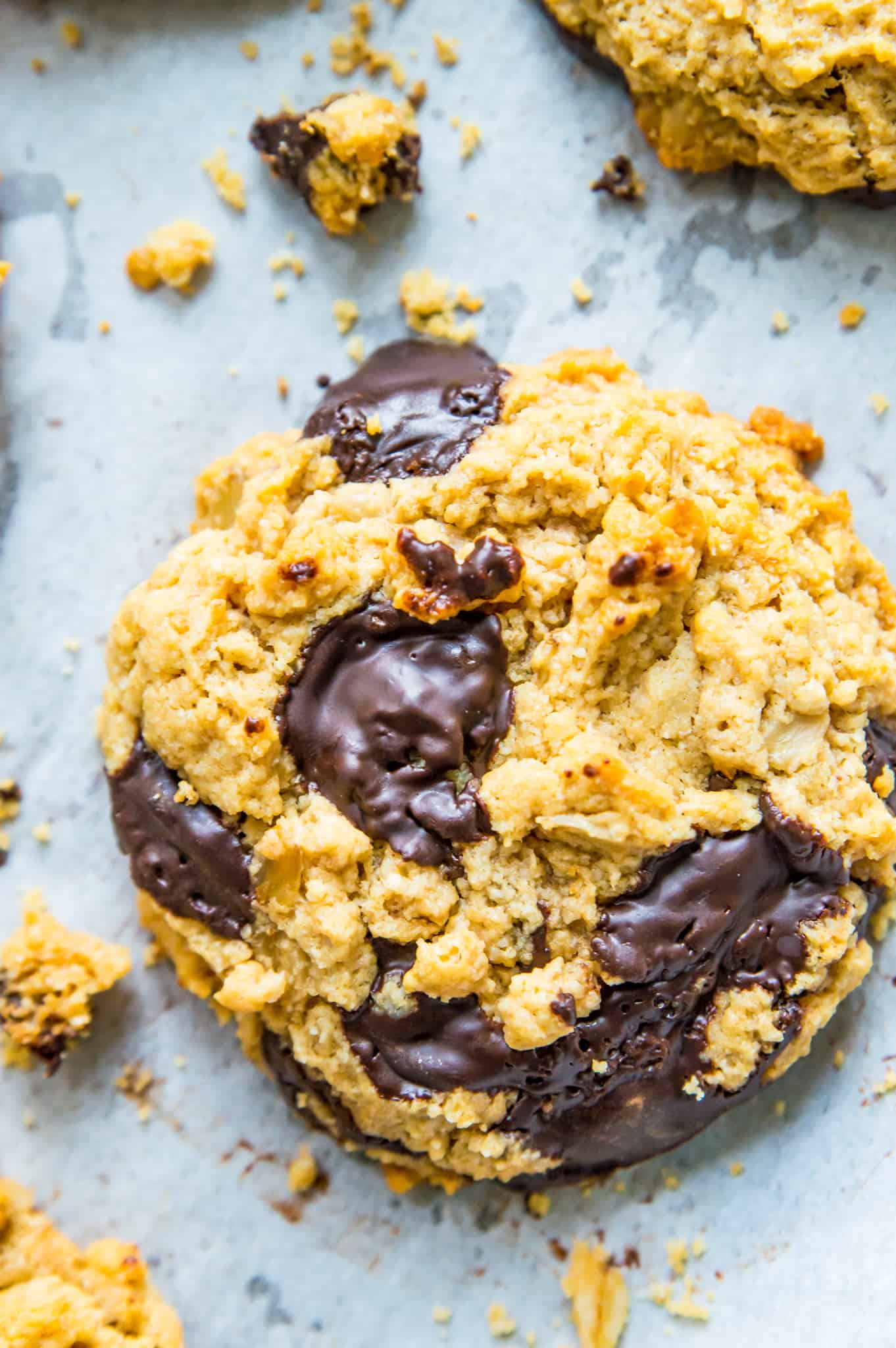 A vegan protein cookie with chocolate with cookie crumbs around it.