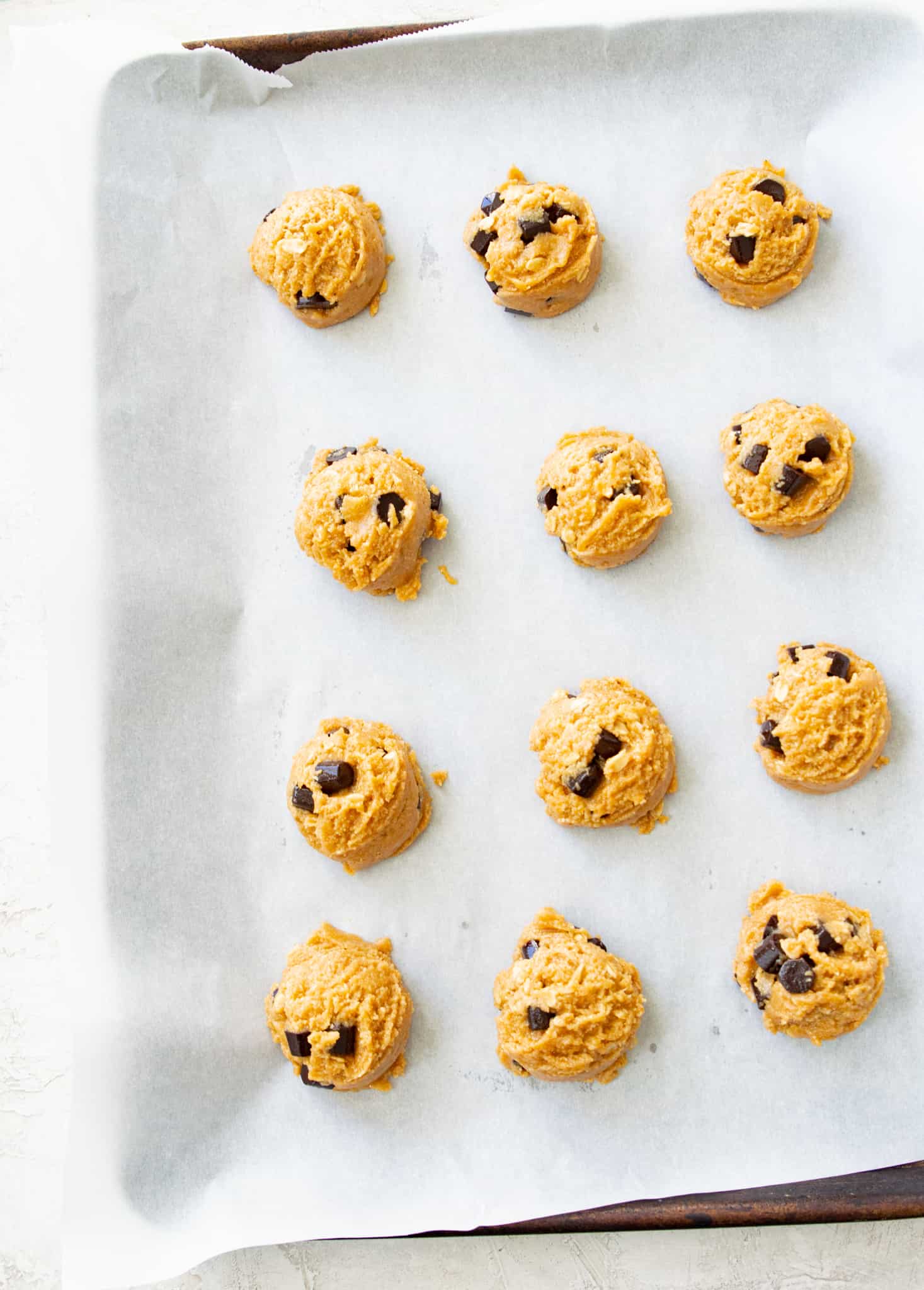 A baking sheet lined with uncooked chocolate chip cookies.