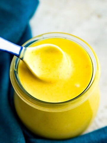 A jar of honey mustard sauce with a spoon in it.
