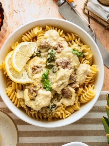 A bowl of spinach and artichoke casserole over noodles.