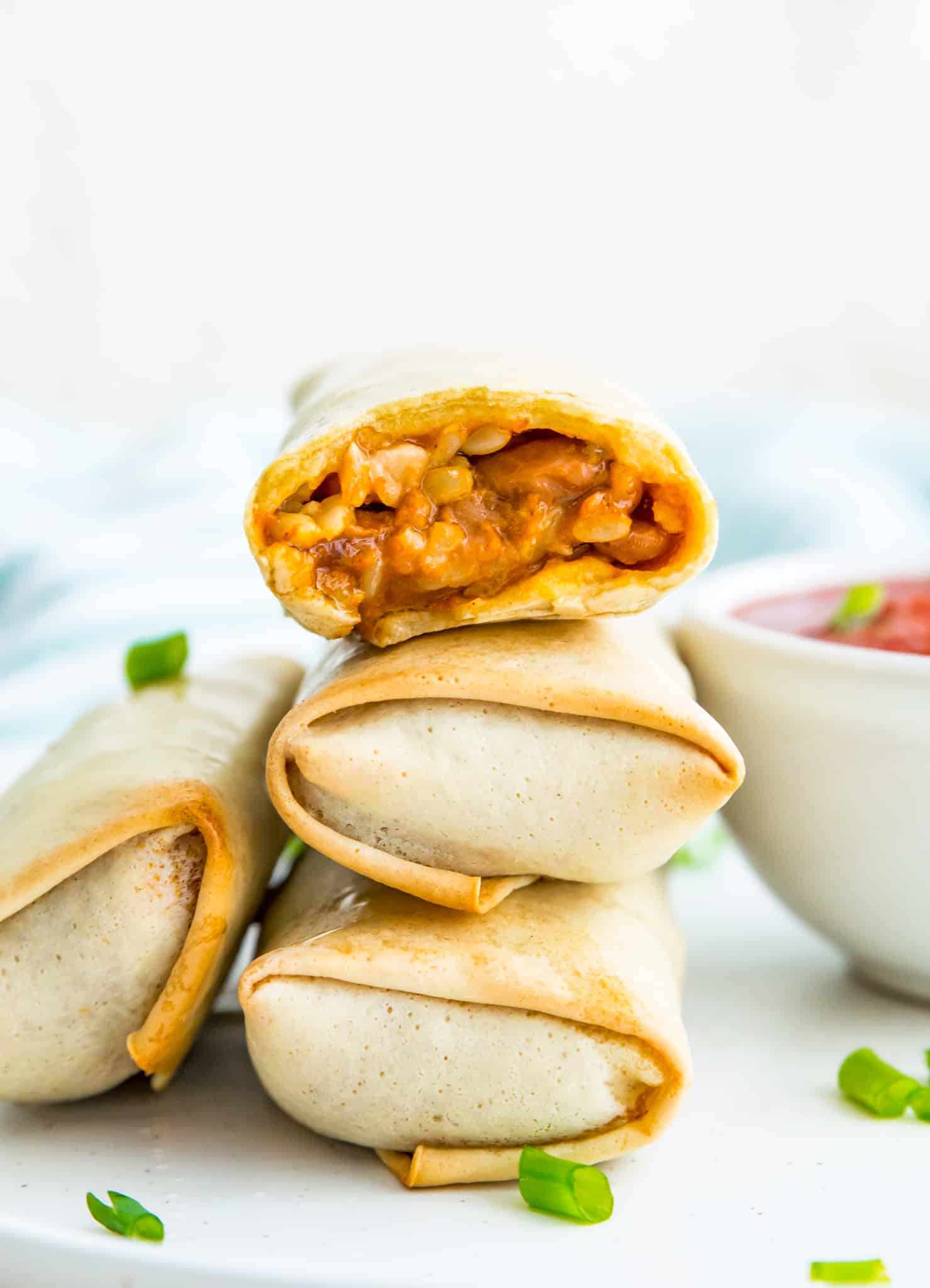 A stack of air fryer burritos and the top one has a bite out of it