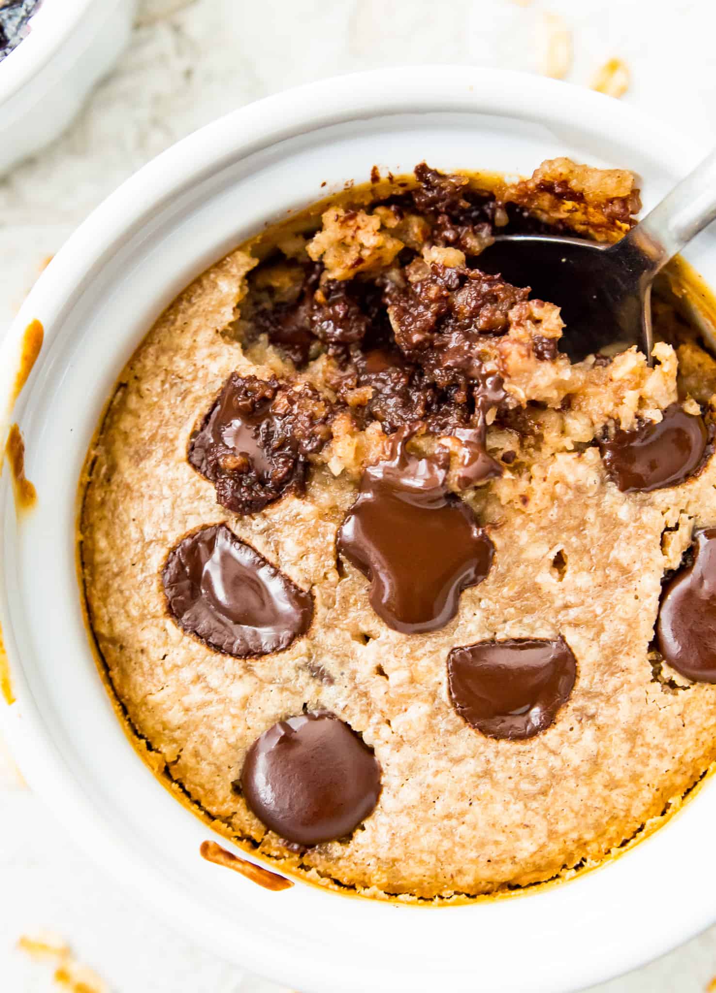 A ramekin filled with chocolate protein baked oats with a spoon in it.