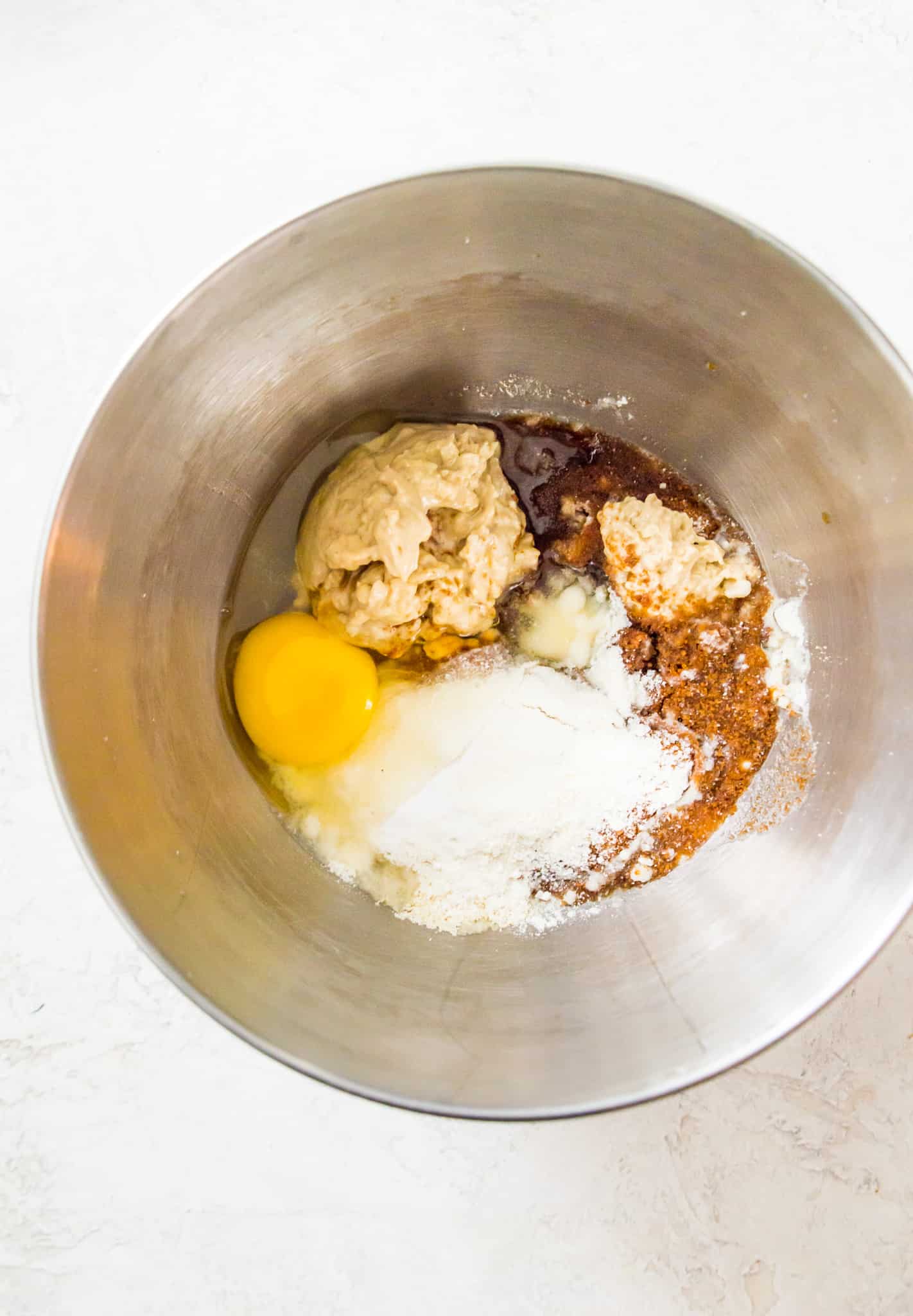 A mixing bowl filled with an egg yolk, almond flour, cashew butter, coconut oil and coconut sugar.