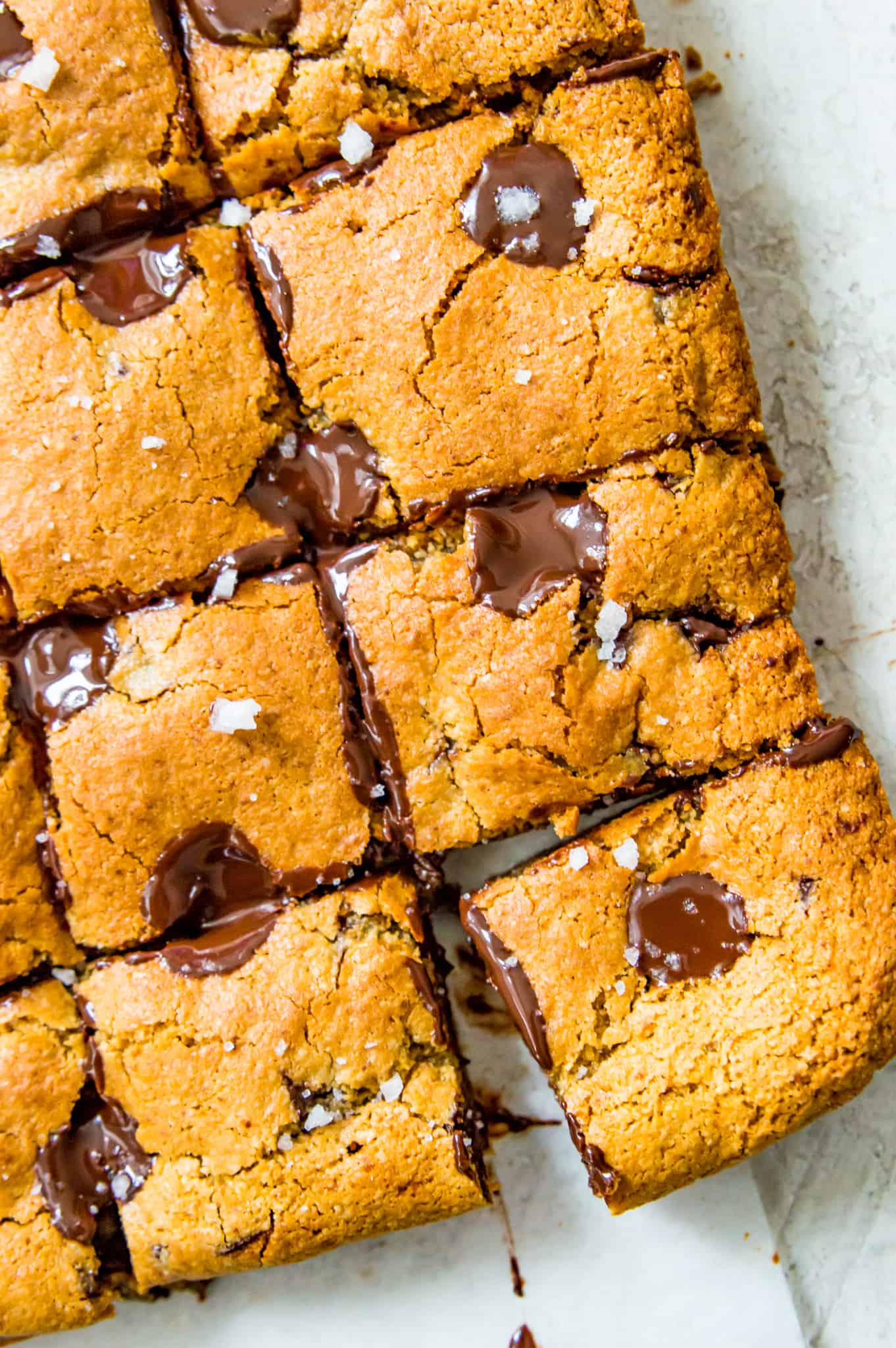 Baked vegan blondies with chocolate that are cut into pieces. 